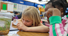 student with a magnifying glass looking at a water environment